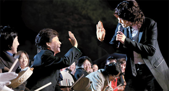 朴槿恵（パク・クネ）大統領が２７日夜、青瓦台（チョンワデ、大統領府）緑地園（ノクチウォン）で開かれた「文化隆盛の韓国の味、韓国の粋－アリラン」公演に参加し、歌手キム・ジャンフンと手の平を合わせてあいさつしている。