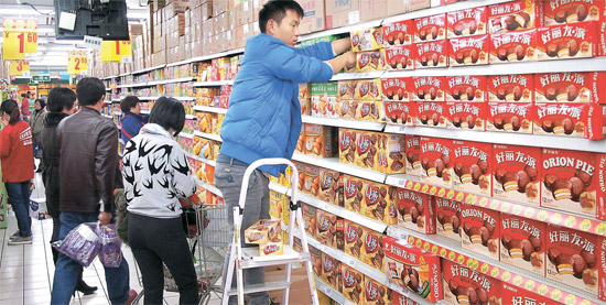 ８日、北京朝陽区にある大型スーパー「京客隆」の食品売り場でショッピング客が好麗友パイなどオリオンの製品を見ている。
