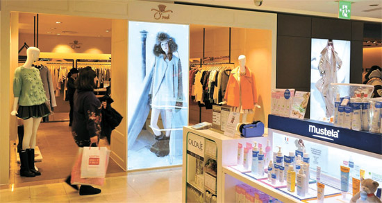 ＳＫネットワークスが運営する女性服ブランド「Ｏ’２ｎｄ（オズセカンド）」が韓国産ブランドとして初めてロッテ・新羅免税店に入店した。ソウル小公洞（ソゴンドン）のロッテ免税店本店で名品ブランド「マックスマーラ（ＭａｘＭａｒａ）」と並ぶ「オズセカンド」の店舗前を顧客が通り過ぎている。（写真＝ＳＫネットワークス）