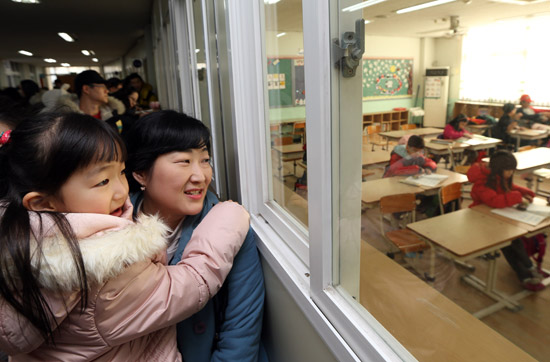 １５日、ソウル望遠洞（マンウォンドン）の小学校で、新入生と母親が冬休みの放課後授業中の教室を見学している。