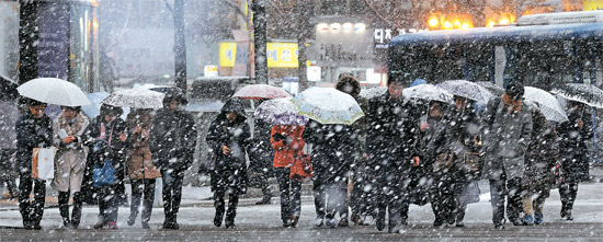 ２０日午後４時頃、ソウル一帯には前が見えないほどの「ぼたん雪」が降りしきった。ソウル市民が久しぶりの本格的な雪の中、南大門（ナムデムン）付近の太平路（テピョンノ）の横断歩道を渡っている。