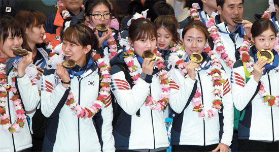 キム・ヨナに大きなチョコメダル…キム・アラン、チョ・ヘリ、パク・スンヒ、イ・サンファ、キム・ヨナ（前列左から）ら２０１４ソチ冬季五輪に参加した韓国選手団が２５日、仁川国際空港で開かれた代表チーム解団式で、大韓体育会が贈ったチョコメダルを持って写真撮影をしている。このメダルは直径９センチ、厚さ１センチの手作りチョコ。キム・ヨナや李奎ヒョクなど今大会を最後に引退する選手は直径１２センチ、厚さ１センチのチョコメダルを受けた。