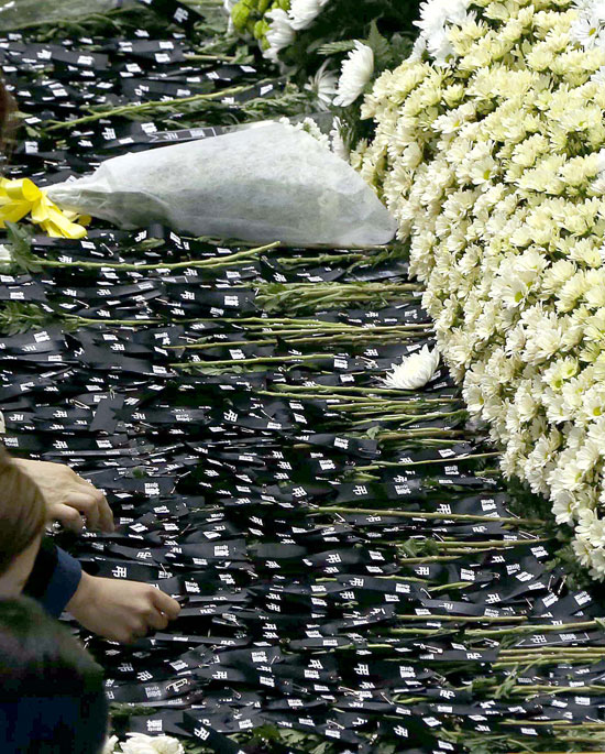 ２７日、セウォル号沈没事故犠牲者臨時合同焼香所で、弔問客が菊の代わりに「謹弔」リボンを献花テーブルに載せている。