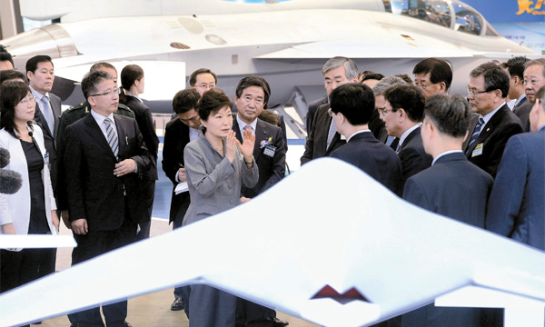 ２９日、京畿道高陽の韓国国際展示場で開かれた民・軍技術協力博覧会でステルス無人偵察機（前方）に対する説明を聞いている朴槿恵大統領。