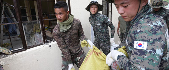 ２４日フィリピンのレイテ州タクロバン市でアラウ部隊員が台風ハイエンで被害を受けたある高齢者施設を復旧させるためにフィリピン軍将兵と共に廃資材を運んでいる。