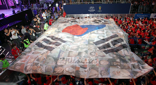 ２７日午前、ソウル三成洞（サムソンドン）ＣＯＥＸの前の永東大路（ヨンドンデロ）で、２０１４ブラジル・ワールドカップ韓国対ベルギー戦を控えてレッドデビルズ（赤い悪魔）が大型太極旗を掲げて応援を繰り広げている。