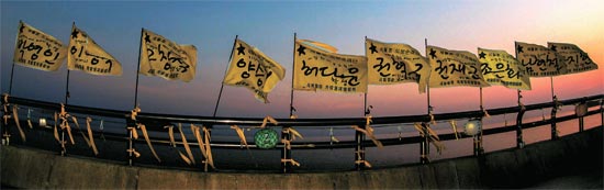２３日、彭木港に翻る不明者１０人の名前が書かれた旗。