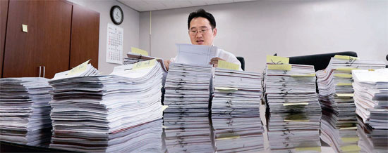 ソウル中央地方裁判所のパク・ドンボク判事が今月に公示送達として処理すべき訴訟書類を調べている。書類に張られた黄色いポスト・イットに、宣告日時と時間が記されている。