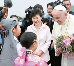 １４日、ソウル空港に到着したフランシスコ法王にソウル啓星小学校の児童が花束と手紙を渡している。（写真＝青瓦台）