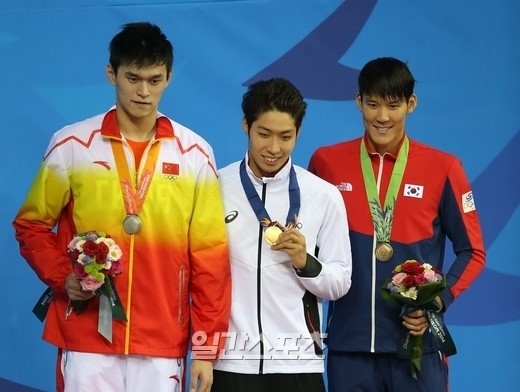 ２１日、男子自由形２００メートル決勝後、表彰台に立った金メダルの萩野公介（写真中）、銀メダルの孫楊（左側）、そして朴泰桓（パク・テファン、右側）。（写真＝ＩＳフォト）