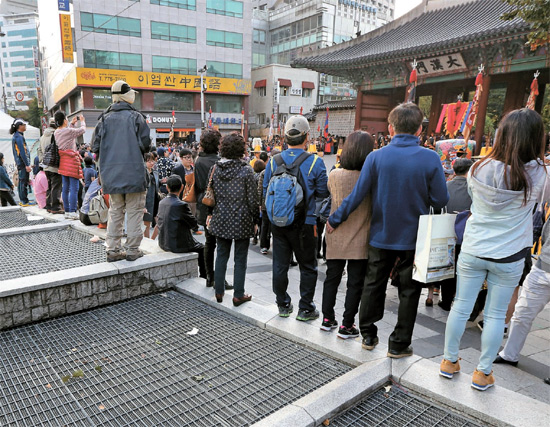 徳寿宮の前は危険＝１８日午後、観光客がソウル大漢門前の地下鉄換気口に上がり、守門将交代式を見ている。ソウルメトロは１９日、換気口への接近を防ぐロープを設置した。