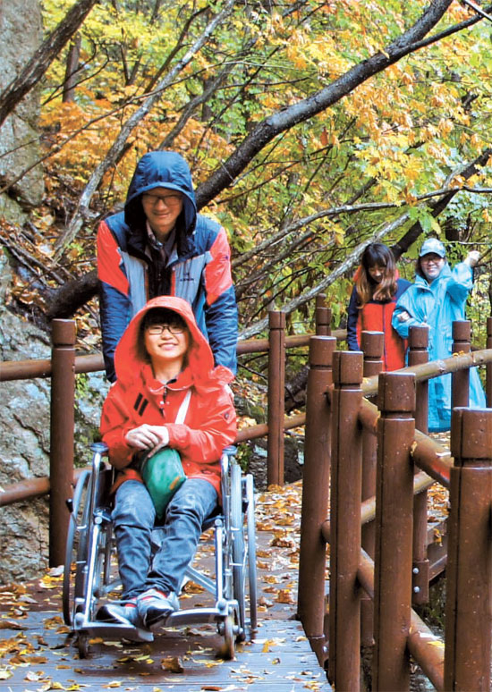車椅子に乗った探訪客が月岳山（ウォラクサン）の紅葉を楽しんでいる。（写真＝国立公園管理公団）