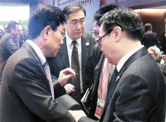 産業通商資源部の尹相直長官（左）が８日に北京で開かれたＡＰＥＣ閣僚会議開始前に出席者らと話をしている。尹長官は韓中ＦＴＡ交渉の韓国首席代表を務めている。（写真＝産業通商資源部）