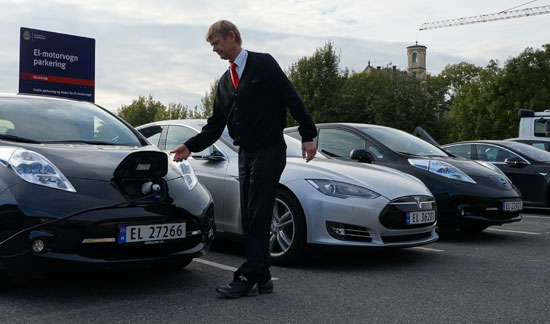 ノルウェーのオスロ中心街アーケルブリッゲに用意された電気自動車専用駐車場でドライバーが自分の電気自動車を充電している。電気自動車の駐車と充電料金は無料だ。