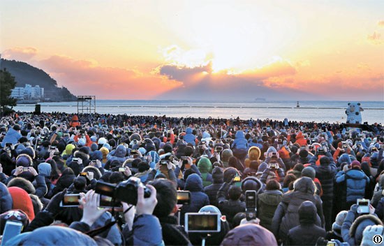 １日午前、釜山の海雲台海水浴場に訪れた市民と観光客が砂浜に集まり初日の出を見つめている。