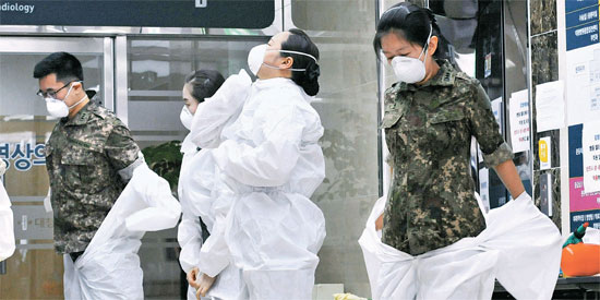 軍医療陣が患者を治療する前、防護服を着ている。