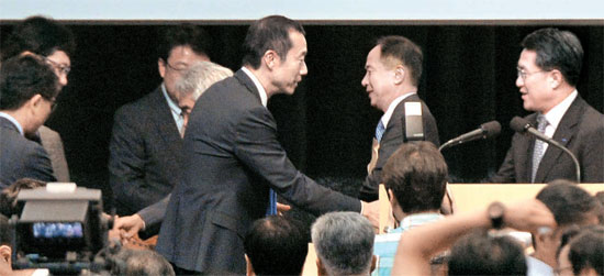 崔治勲（チェ・チフン）サムスン物産社長（真ん中）が株主総会を終えた後、李栄鎬（イ・ヨンホ）サムスン物産副社長（右）と握手している。