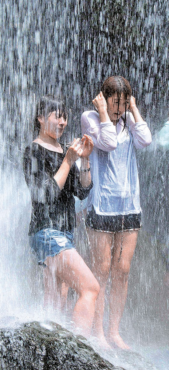 ３０日、全羅南道求礼郡の智異山・水落の滝を訪れた避暑客が滝に当たって涼んでいる。