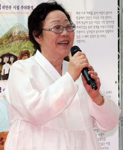 韓服を着た李おばあさんが１０日、国会で開かれた慰安婦被害者の臨床美術治療作品展で愛唱曲を歌っている。