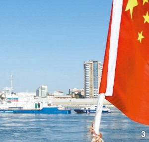 アムール川を行き来する中国遊覧船の五星紅旗の後ろにロシア国境守備隊の警備艦が見える。