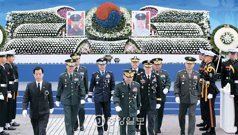 延坪島砲撃挑発５周忌行事が２３日にソウルの戦争記念館平和の広場で開かれた。この日の追悼式には北朝鮮の奇襲挑発で犠牲となったソ・ジョンウ下士とムン・グァンウク一等兵の遺族、政府と各界要人ら４０００人余りが参加した。韓民求国防部長官（左）と各軍指揮官が参拝を終えた後壇上から降りてきている。