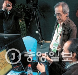 ミリンバレー杯世界コンピュータ囲碁決勝戦でイム代表（右）が日本の「ＺＥＮ」の開発者尾島陽児氏ともに「トルバラム」の対局状況を見守っている。
