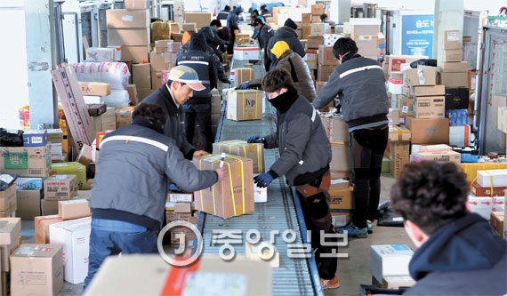 ３日、釜山市東区（プサンシ・ドング）ＣＪ大韓通運南部山ターミナルで宅配運転手が箱を地域別に仕分けしている。運転手は箱１個あたり配送料として８００ウォン（７８円）を受け取っている。