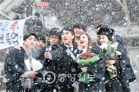１６日、ソウル麻浦区の西江大学位授与式で卒業生がボタン雪が舞う中で記念撮影をしている。