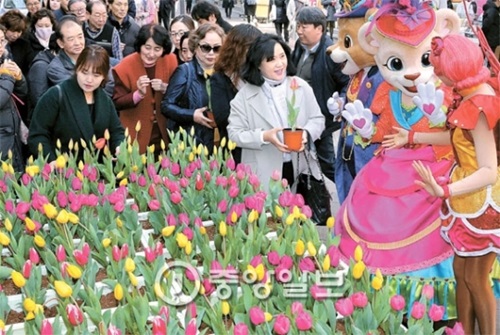 エバーランドのチューリップ祭り（３月１７日～４月２４日）を控えた１５日、同テーマパークの代表キャラクターである「レニーとララ」がソウル明洞（ミョンドン）の通りで市民にチューリップの植木鉢を配っている。