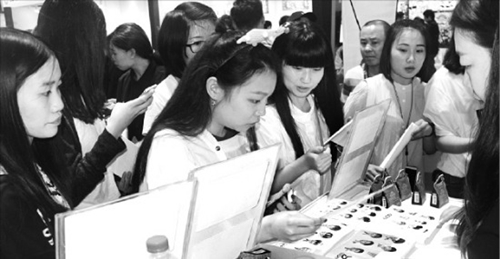 大韓貿易投資振興公社（ＫＯＴＲＡ）が２０日に中国の重慶で開いた韓流商品博覧会で、観覧客が化粧品やアクセサリーなどの展示商品を見ていた。