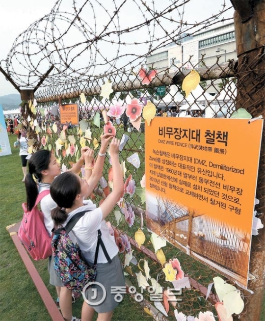 ２７日、学生が「統一博覧会２０１６」で、南側非武装地帯に設置されていた鉄柵に希望のメッセージを付けている。