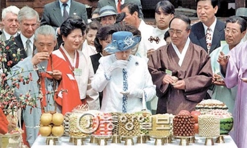 １９９９年、韓国伝統の誕生日祝膳の前で祝杯用の清酒を試飲するエリザベス２世（真ん中）。（中央フォト）