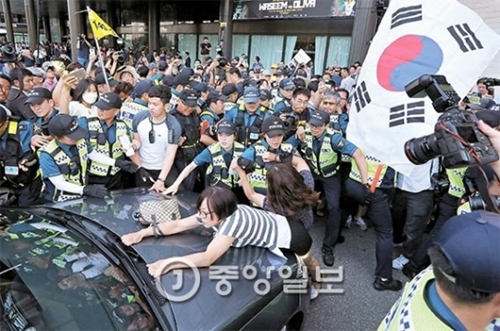 １２日、日本自衛隊創設６２周年記念行事が開かれたミレニアム・ソウル・ヒルトン前で、韓国の市民団体のメンバーが日本大使館車両の侵入を阻止している。