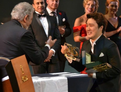 オペラリアコンクール１位の韓国テノール歌手のキム・ゴヌ（右）がドミンゴからトロフィーを受け取っている。（写真＝オペラリアコンクール）
