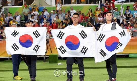 イ・スンユン、キム・ウジン、ク・ボンチャン（左から）が試合後に太極旗を持って歓呼している（写真＝五輪写真共同取材団）