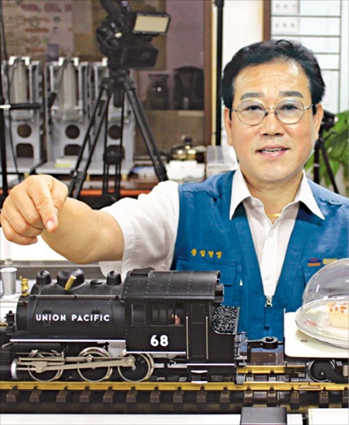 オリオン食品機械のオム・チョンソプ社長が小型のおもちゃの汽車を利用した食べ物配達システムを説明している。