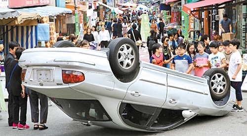 世界カーフリーデーを翌日に控えた２１日、釜山市東区庁の主催でイベント「車のない道路で遊んでみよう」が開催された。小学生たちが展示「裏返された乗用車」を見ている。