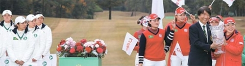 優勝トロフィーを持って笑顔を見せる韓国選手団の主将・申智愛（シン・ジエ、右）。韓国は最終日の日本とのシングルマッチ８競技で７勝１分けと圧勝した。左は準優勝した日本の選手団。（写真＝ＫＬＰＧＡ）
