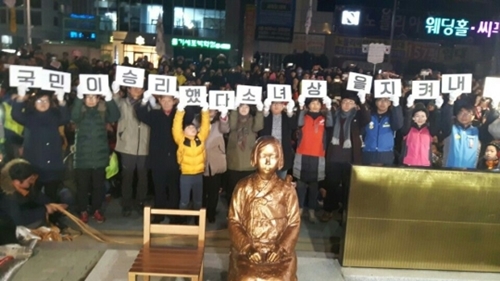 2016年12月３１日午後９時、釜山市東区の日本領事館前に設置された平和の少女像の周りで釜山市民らが「国民の勝利だ」「少女像を守り抜こう」というピケットを手にしている。（写真＝釜山警察庁）