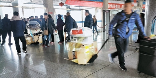 ２１日、中国山東省威海国際旅客ターミナルで中国人商人が荷物を引いて出てきている。