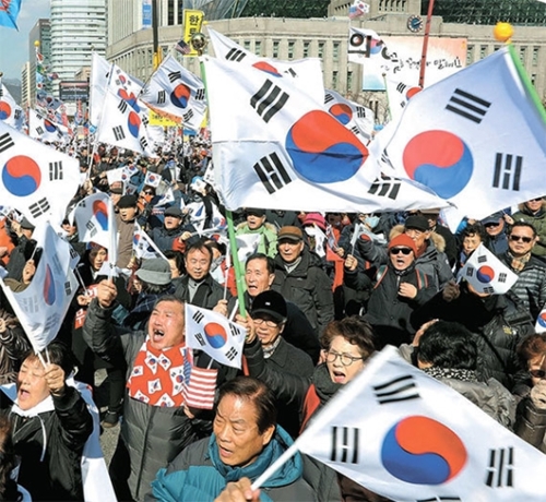 朴槿恵大統領弾劾賛否集会が２５日、ソウル世宗路で開かれた。反対集会の参加者が大漢門の前で大極旗を振っている。