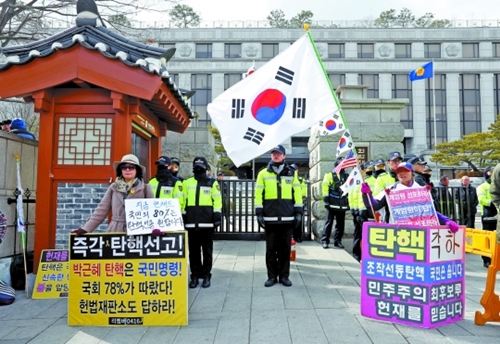 朴槿恵大統領の弾劾審判宣告を２日後に控えた８日、憲法裁判所前で弾劾に賛成する市民（左）と反対する市民がそれぞれ１人デモを行っている。