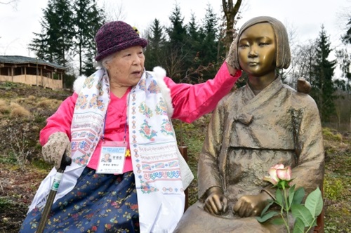 慰安婦被害者のアン・ジョムスンさんが８日、ドイツバイエルン州ウィーゼント「ネパール・ヒマヤラ・パビリオン公園」に設置された「平和の少女像」を撫でている。（写真＝水原市）