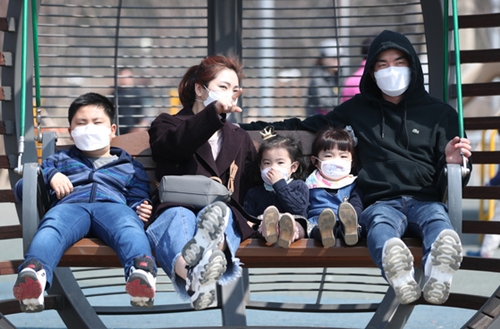 １９日、ソウル蘭芝漢江公園でマスクをつけたままブランコに乗っている家族。