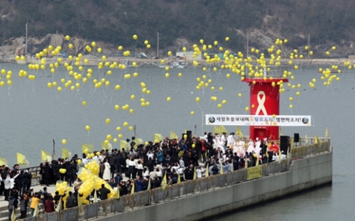珍道郡は２８日、彭木港を訪れた追慕客と共にセウォル号未揚収者の安全な収拾を祈ってセウォル号移送前に慰霊祭を開き、黄色い風船を飛ばしている。