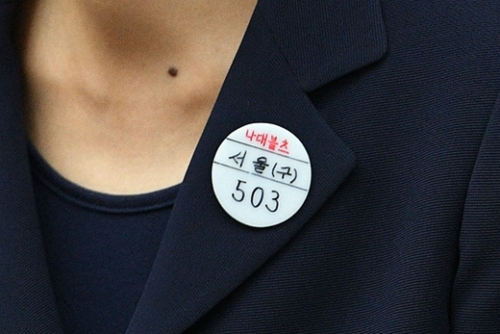 ２３日、朴槿恵前大統領が胸元に付けているバッジ。ほかの共犯者と隔離・管理するために、識別符号として上部に赤い文字で「ナデブルツ」と記されている。