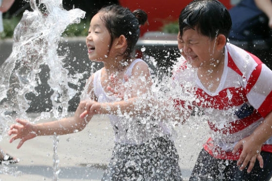 １６日午後、ソウル光化門（クァンファムン）広場の噴水で遊ぶ子どもたち。