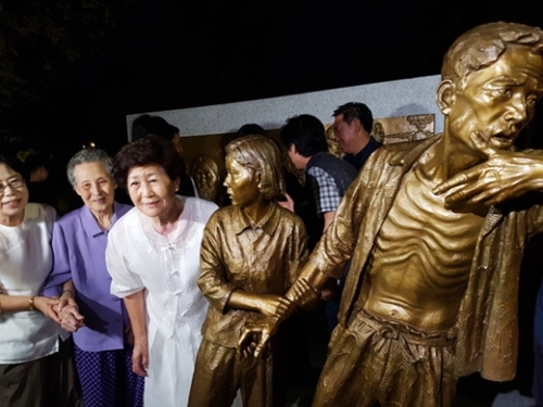 日帝強占期に強制徴用された労働者を称える強制徴用労働者像「解放の予感」が全国で初めて１２日に仁川の富平公園に建てられた。銅像の「娘」のモデルとなったチ・ヨンレさん（左端）と「父親」のモデルであるイ・インヒョンさんの娘のイ・スクチャさん（左から２人目）が銅像の前で記念撮影をしている。