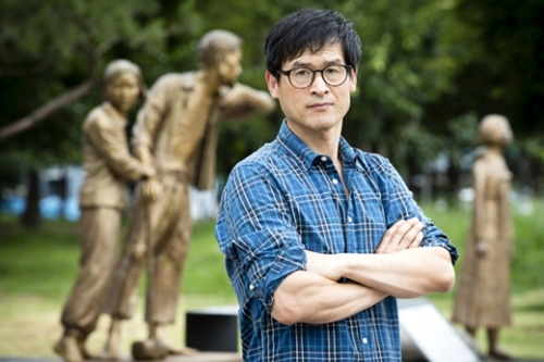 １４日、仁川冨平公園の「徴用労働者像」を背景に立っている彫刻家イ・ウォンソクさん。