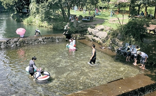 夏の休暇シーズンを迎えて済州道を訪れた観光客が西帰浦市チョンモシ憩いの場で水遊びをしている。今年済州では中国人団体観光客が急減した一方、韓国人と日本人観光客は大きく増えている。